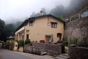 a building next to a stone wall and a building at Alasia Hotel in Kasauli