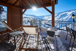 eine Veranda mit Stühlen und Blick auf die schneebedeckten Berge in der Unterkunft Alpenhotel Laurin in Hochgurgl