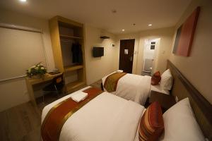 セブシティにあるNS Royal Hotelのベッド2台とデスクが備わるホテルルームです。