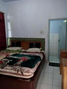 Schlafzimmer mit einem Bett und einer Glasdusche in der Unterkunft Sri Dewi Homestay in Ranuyoso