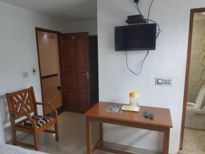 a room with a table and a tv on the wall at Princess Residency in Nedumbassery