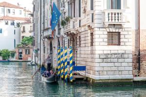 un hombre en una góndola en un canal al lado de un edificio en Hotel Ai Cavalieri di Venezia, en Venecia