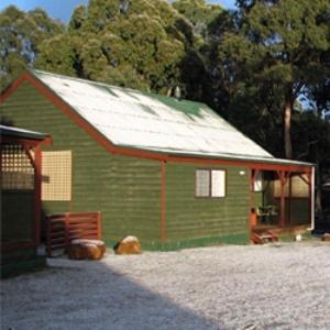 a green barn with a white roof and trees at Derwent Bridge Chalets & Studios in Derwent Bridge