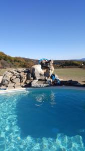 een groot zwembad met blauw water en rotsen bij chambre d'hôtes in Rousson