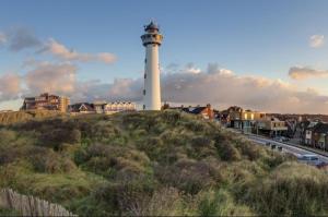 un faro en la cima de una colina al lado de una ciudad en Viale, en Egmond aan Zee
