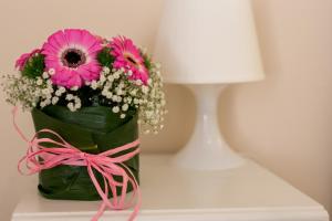 um vaso verde com flores cor-de-rosa numa mesa em B&B Maria Chiara em Toritto