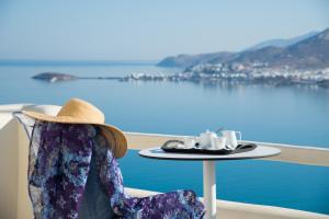 Naxos Rock Villas في ستيليدا: امرأة تجلس على طاولة مع صينية من أكواب الشاي