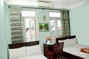 a bedroom with two beds and a table with a chair at Cat An Guesthouse in Hue