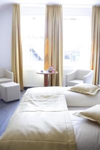 a bedroom with two beds and chairs and a large window at Hotel Goldene Krone in Clausthal-Zellerfeld