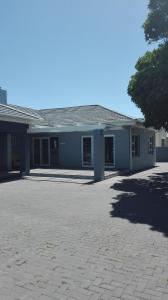 a blue building with a large driveway in front of it at Garden Gate Guest House in Port Elizabeth