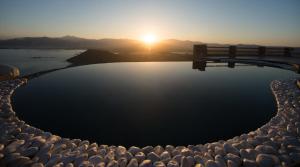 a pool of water with the sunset in the background at Naxos Rock Villas in Stelida