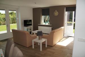 ein Wohnzimmer mit Sofas, einem Tisch und einem TV in der Unterkunft Vakantiehuizen Hofstede Elzenoord in Vrouwenpolder