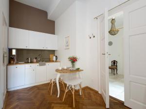 - une cuisine avec des placards blancs, une table et des chaises dans l'établissement Antique Apartments Old Town, à Cracovie