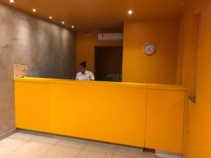 a man standing behind a yellow counter in a restaurant at Ouro Motel in Sepetiba +24 photos
