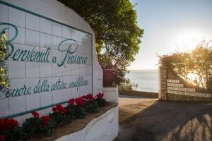 a sign with red flowers next to the ocean at Hotel Piccolo Sant'Andrea in Praiano