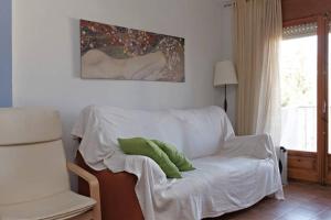 a living room with a white couch with two green pillows at Apartamento Pau Casals in L'Ametlla de Mar