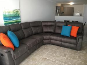 un sofá marrón con almohadas coloridas en la sala de estar. en Geographe Bay Apartment, en Busselton