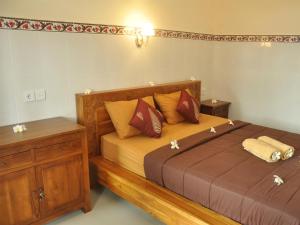 sypialnia z drewnianym łóżkiem z poduszkami w obiekcie Mira Family Homestay w mieście Ubud