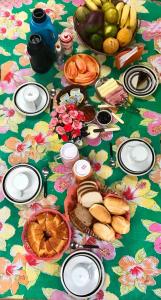 una mesa con comida y fruta en un mantel floral en Pousada Tia Cleide en Caraguatatuba
