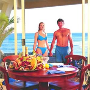 Al Mare Beachfront Retreat Award Winner في ذا إينترانس: رجل وامرأة في بدلات السباحة يقفان على طاولة