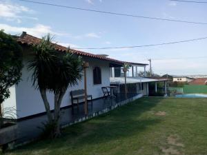 a white house with a yard with a palm tree at Pousada Tourne Bride in Araruama