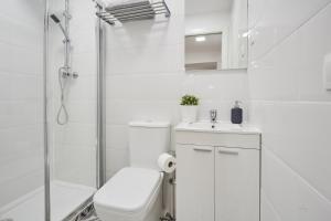 a white bathroom with a toilet and a shower at LEEWAYS APARTMENT in SAN LORENZO in Madrid