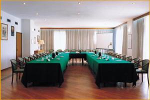 une grande salle de réunion avec des tables et des chaises vertes dans l'établissement Park Hotel Galileo, à Reggello