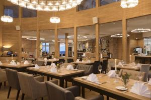 un restaurante con mesas de madera, sillas y lámparas de araña en Hotel Brunnenhaus Schloss Landau en Bad Arolsen