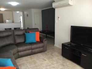 a living room with a brown couch and a flat screen tv at Geographe Bay Apartment in Busselton