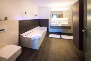 a bathroom with a tub and two sinks and a mirror at View & Garden Villa Schauenstein in Schauenstein