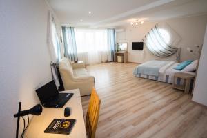 uma sala de estar com uma cama e uma secretária com um computador portátil em Robinzon Hotel em Anapa