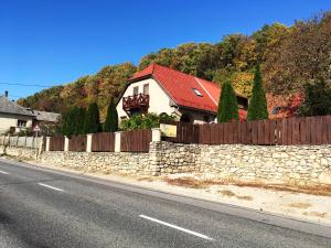 a house on the side of a road with a stone wall at Bóbita Háza in Eplény