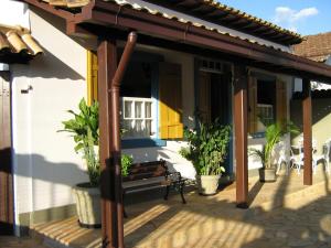 a porch of a house with a bench and plants at Pousada Amaryllis in Tiradentes