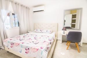 1 dormitorio con cama, silla y espejo en Asher's Apartments, en Eilat