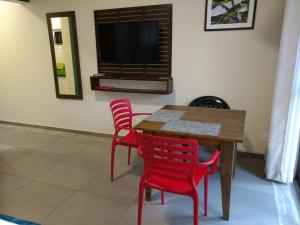 een eettafel met rode stoelen en een televisie bij Studios Formanabá in Florianópolis