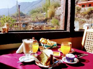 a table with a plate of food and glasses of orange juice at Mai Jaii in Purmamarca