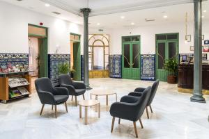 une salle d'attente avec des chaises, des tables et des portes vertes dans l'établissement Hotel Inglaterra, à Grenade