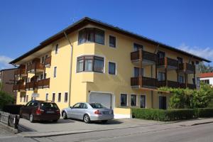 dwa samochody zaparkowane przed żółtym budynkiem w obiekcie Hotel garni Vogelsang w mieście Bad Füssing