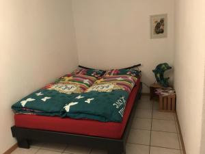 Studio Noyer C في لوكرباد: غرفة نوم مع سرير مع لحاف احمر وأخضر