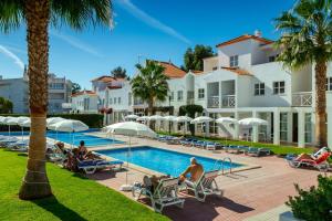 a group of people sitting around a pool at a resort at Club Ouratlantico in Albufeira