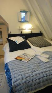 a bed with two pillows and magazines on it at B&B kamers en meer Het Spookhuis in Den Hoorn
