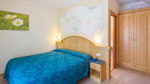 a bedroom with a blue bed and a painting on the wall at Hotel Florida in Molveno