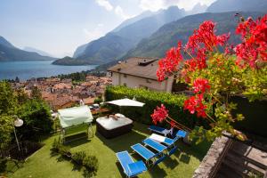 un jardín con sillas, una mesa y un lago en Hotel Florida, en Molveno