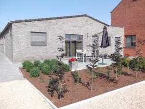 a patio with a table and an umbrella and plants at De Schaapskooi in Kasterlee