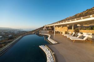 a house with a infinity pool with chairs and water at Naxos Rock Villas in Stelida