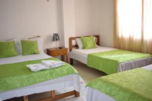 a bedroom with two beds with green and white sheets at Hotel Comercial Neiva in Neiva