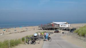 a group of people standing on a sidewalk next to a beach at Holiday home Jong in Schagerbrug