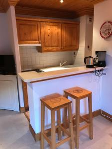 a kitchen with wooden cabinets and two stools at Le Tremplin in Méribel