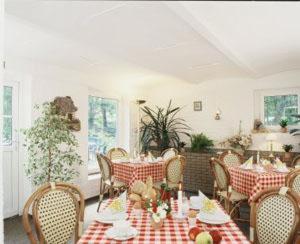 ein Esszimmer mit einem Tisch mit roten und weißen karierten Tischen und Stühlen in der Unterkunft Landguthotel Hotel-Pension Sperlingshof in Dallgow