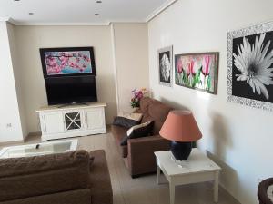 a living room with a couch and a tv at GEMELOS 26 APARTMENTS - Benidormland in Benidorm